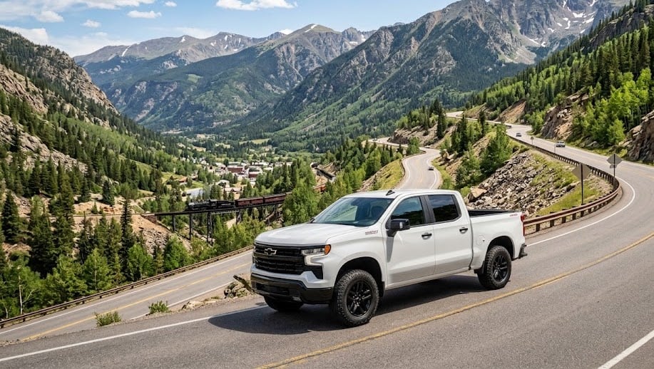 A white 2026 Chevy Silverado 1500 RST with a clean exterior and aggressive stance climbs a winding asphalt highway