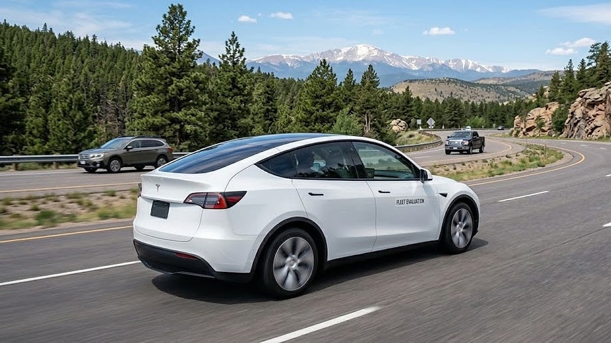 A white 2026 Tesla Model Y traverses a winding Colorado mountain highway during a long-term fleet chassis endurance evaluation
