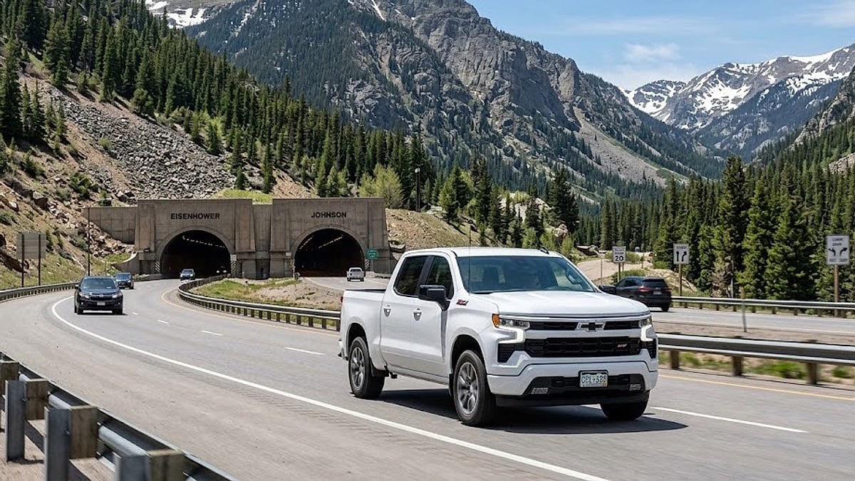 A white Chevrolet Silverado truck travels along a mountain highway approaching the Eisenhower-Johnson Memorial Tunnel in the Colorado Rockies