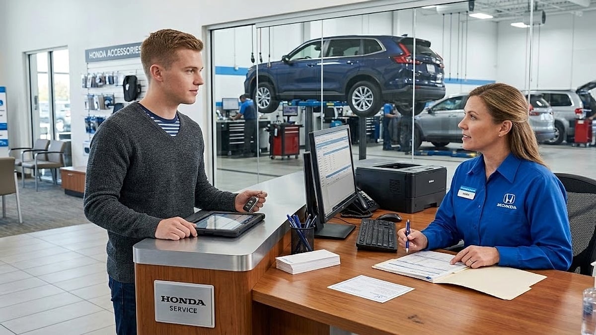 A young male vehicle owner discusses repair paperwork with a Honda service advisor at a dealership service department desk