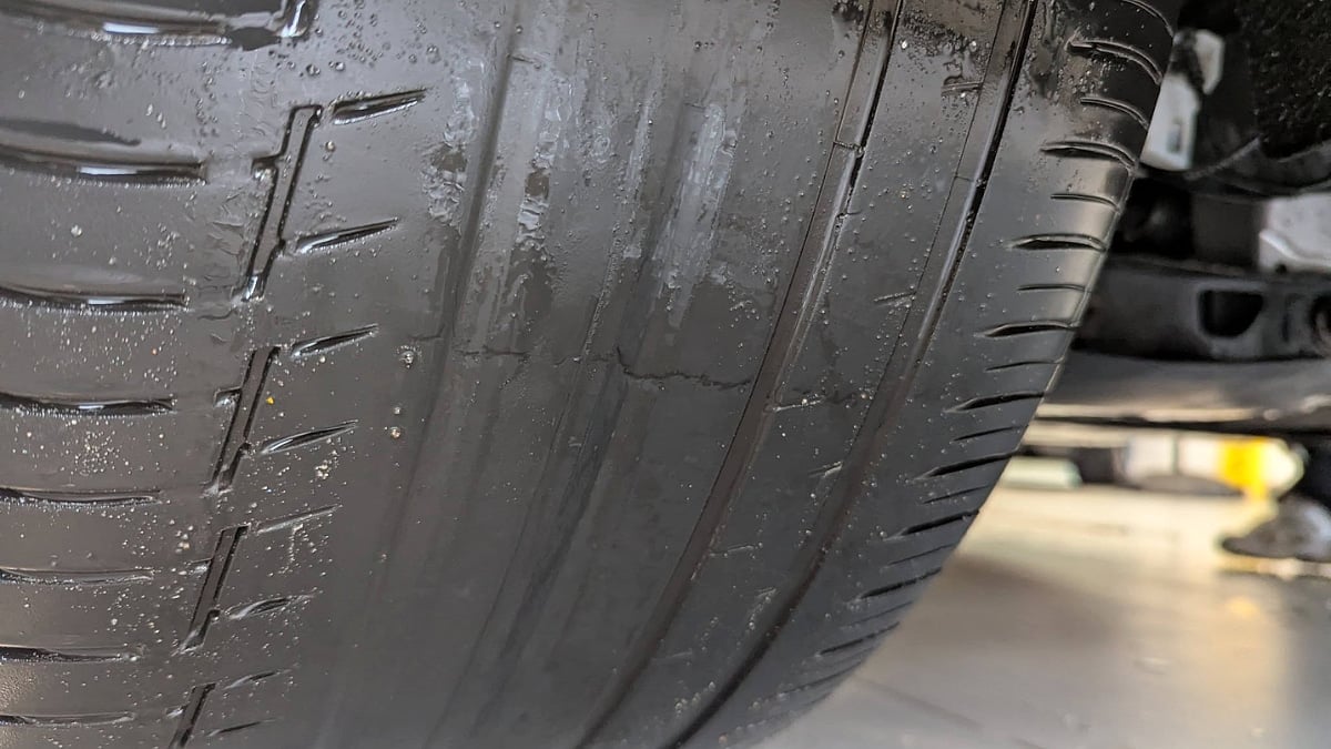 Close-up of a BMW tire showing severe inner-edge wear with most of the tread worn away.