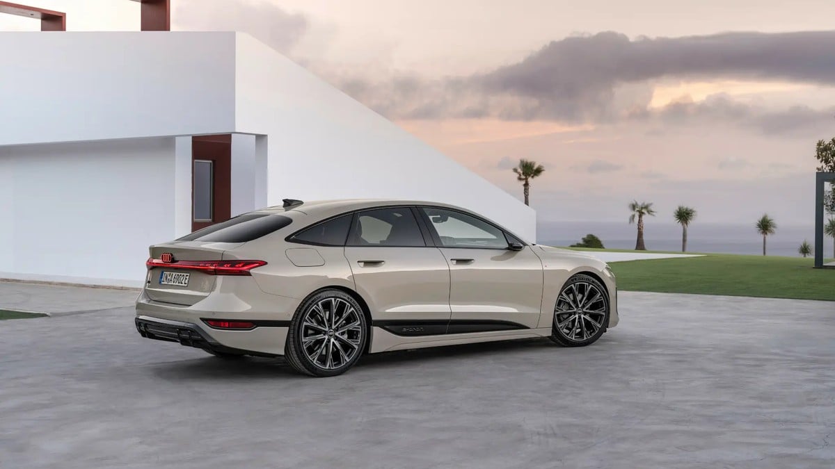 Pearl white Audi e-tron GT electric luxury sedan parked in front of a modern minimalist home at sunset