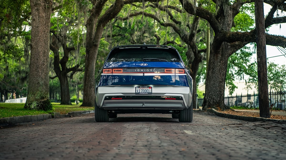 Blue Hyundai Ioniq 5 shown from the rear on an oak-lined brick street with hanging moss.