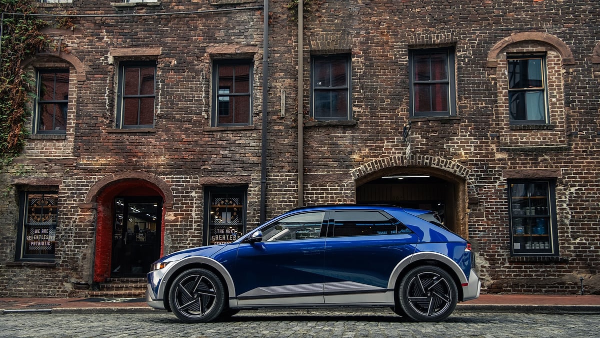 Blue Hyundai Ioniq 5 parked in side profile on a brick street in front of historic brick buildings.