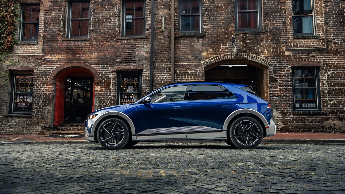 Blue Hyundai Ioniq 5 parked in side profile on a brick street in front of historic brick buildings.