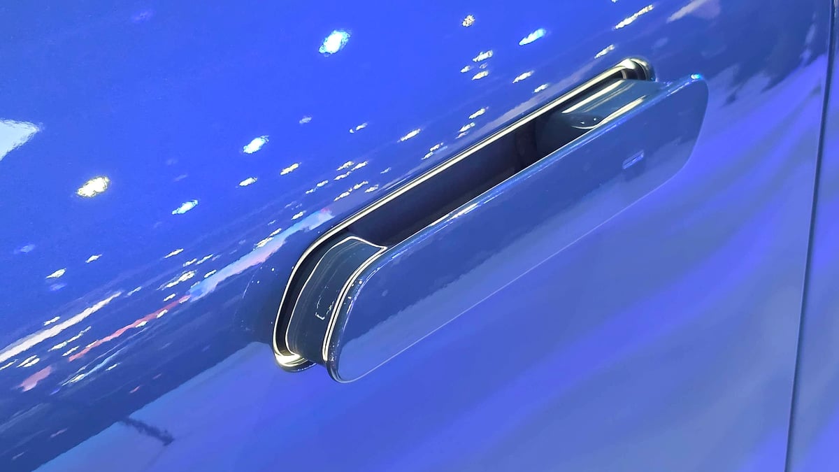 Close-up of chrome flush door handle on glossy blue BMW iX3 electric SUV body panel