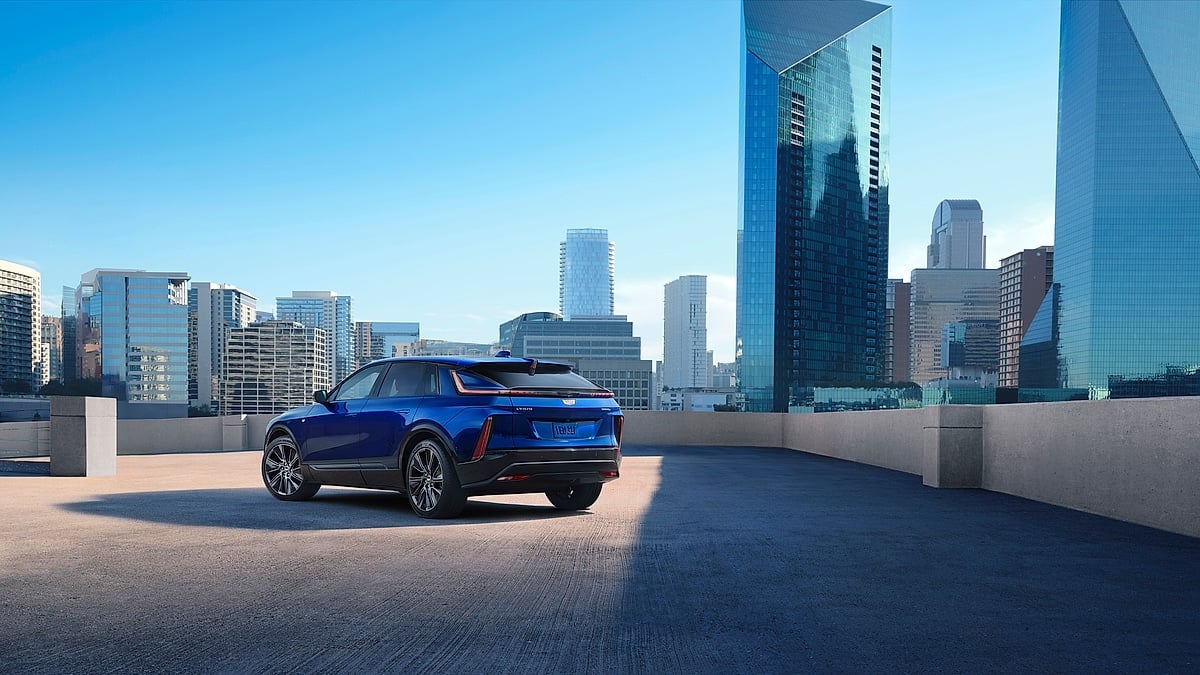 Blue Cadillac Lyriq parked on a rooftop with city skyscrapers in the background.