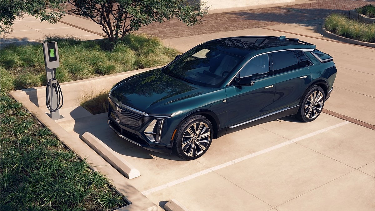 Green Cadillac Lyriq parked in an EV charging space beside a charger.