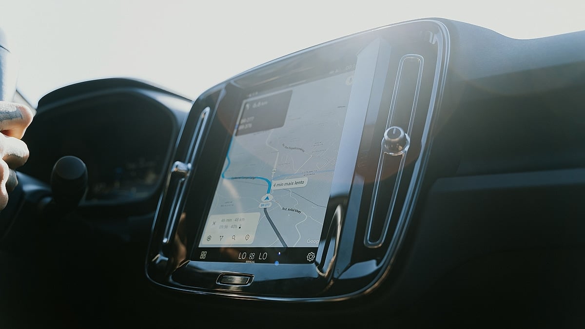 Car infotainment screen showing navigation directions on a sunlit dashboard.