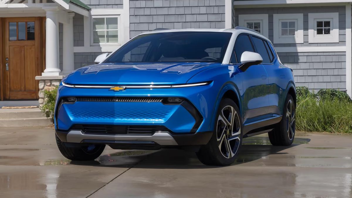 Blue 2024 Chevrolet Equinox EV parked in residential driveway with modern home