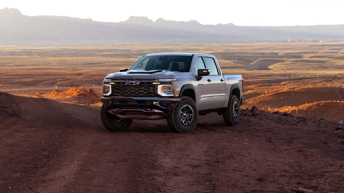 Gray Chevrolet Silverado ZR2 pickup truck parked on a desert dirt road at sunset, front three-quarter view