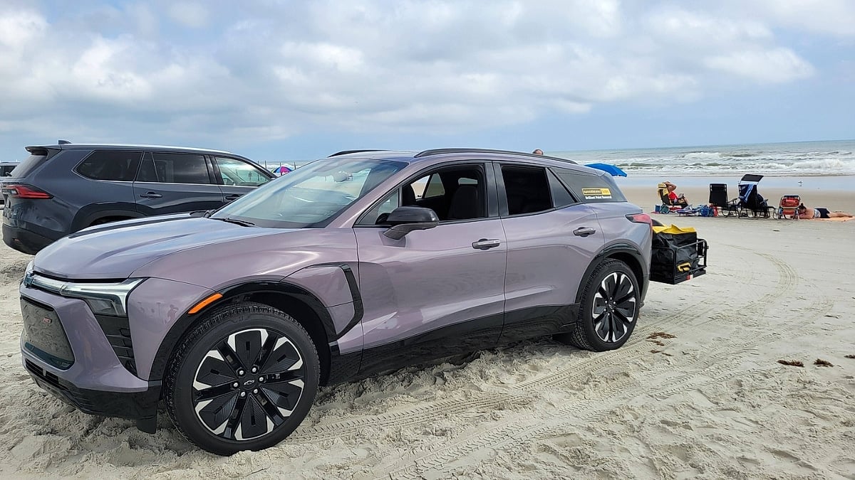 Christopher’s Chevy Blazer EV parked on the beach with a rear cargo carrier attached and the ocean in the background.