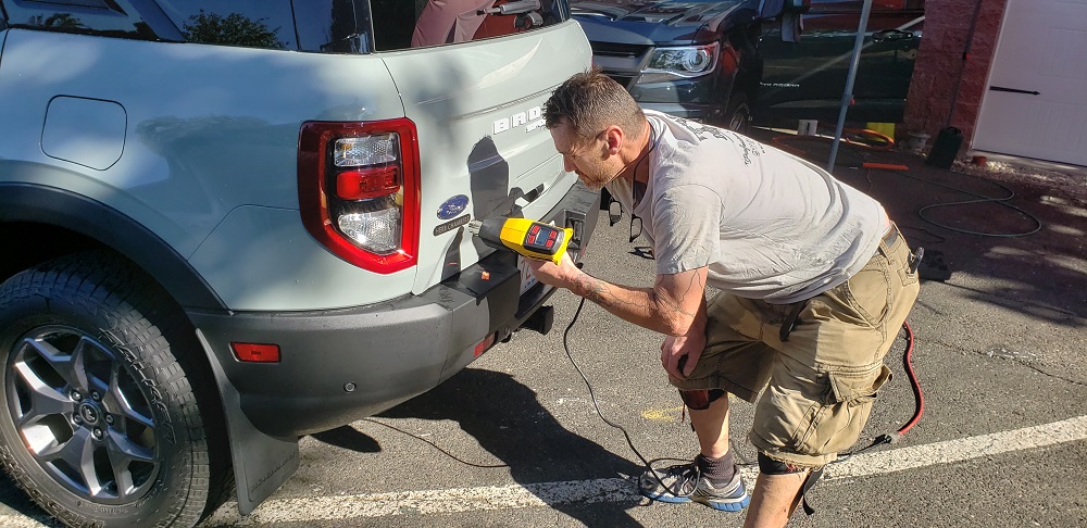 Image of detailer removing dealer sticker from car by John Goreham