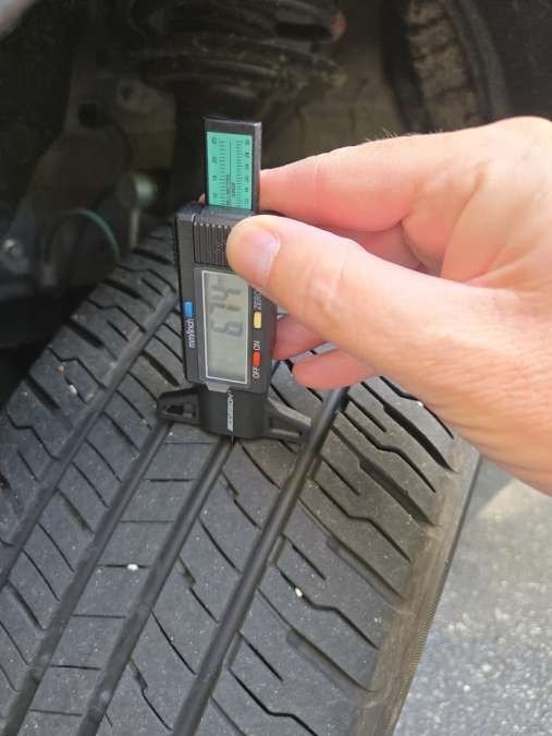 A Dunlop Grandtrek PT20 A/S Tire is shown being measured for tread depth