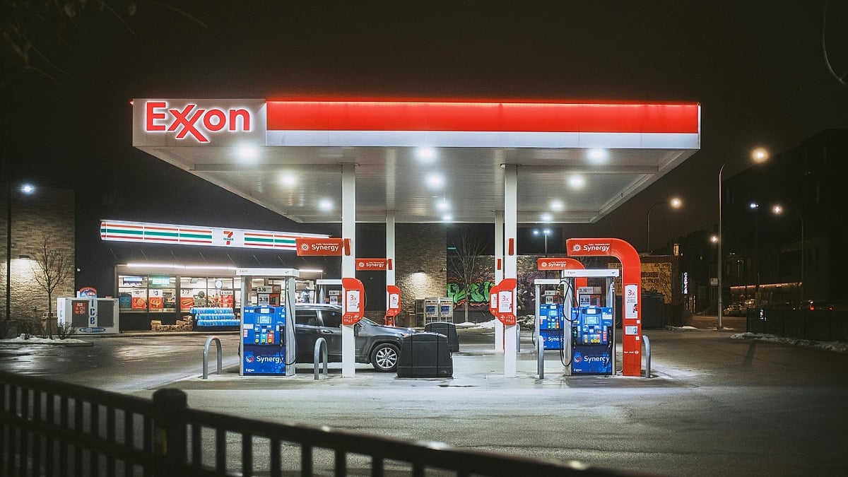 Exxon gas station illuminated at night with fuel pumps and a convenience store in the background.