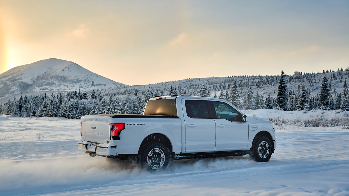 White f-150 Lightning driving through snowy landscape