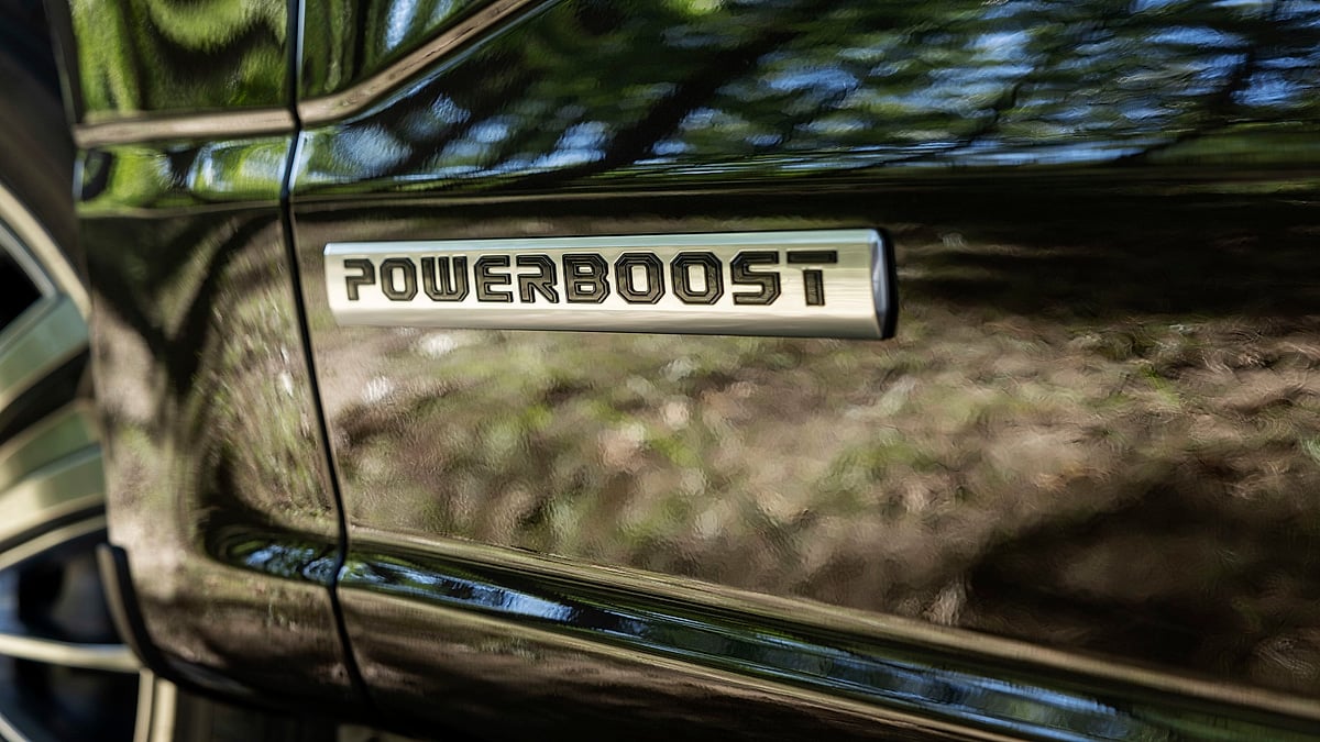 Close-up of a Ford F-150 PowerBoost badge on the side of a black pickup truck.