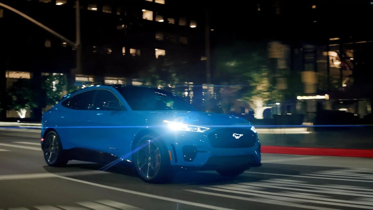 Blue Ford Mustang Mach-E GT driving at night on urban street
