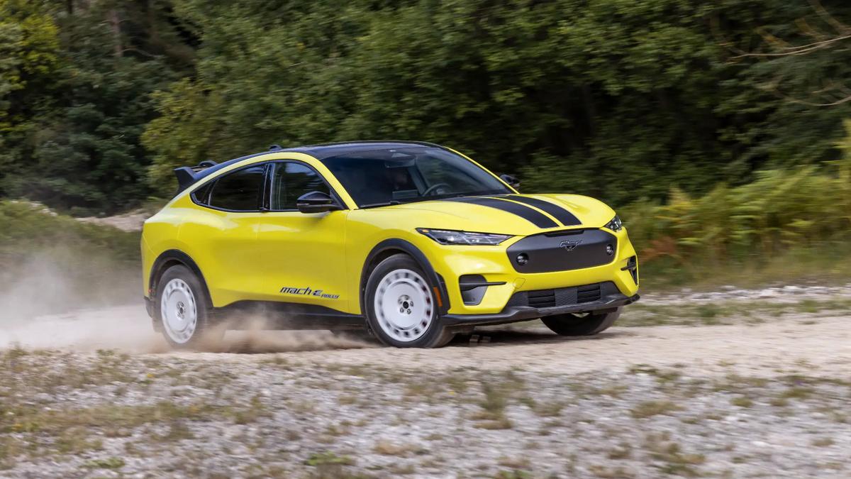 Yellow Ford Mustang Mach-E Rally electric SUV driving at speed on a forest road