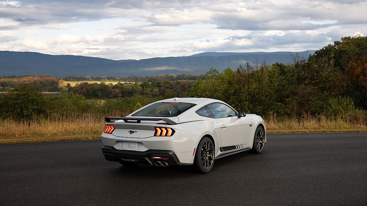 White Ford Mustang RTR Stage 3 rear view showing large wing spoiler, quad exhaust and sequential taillights with mountain scenery