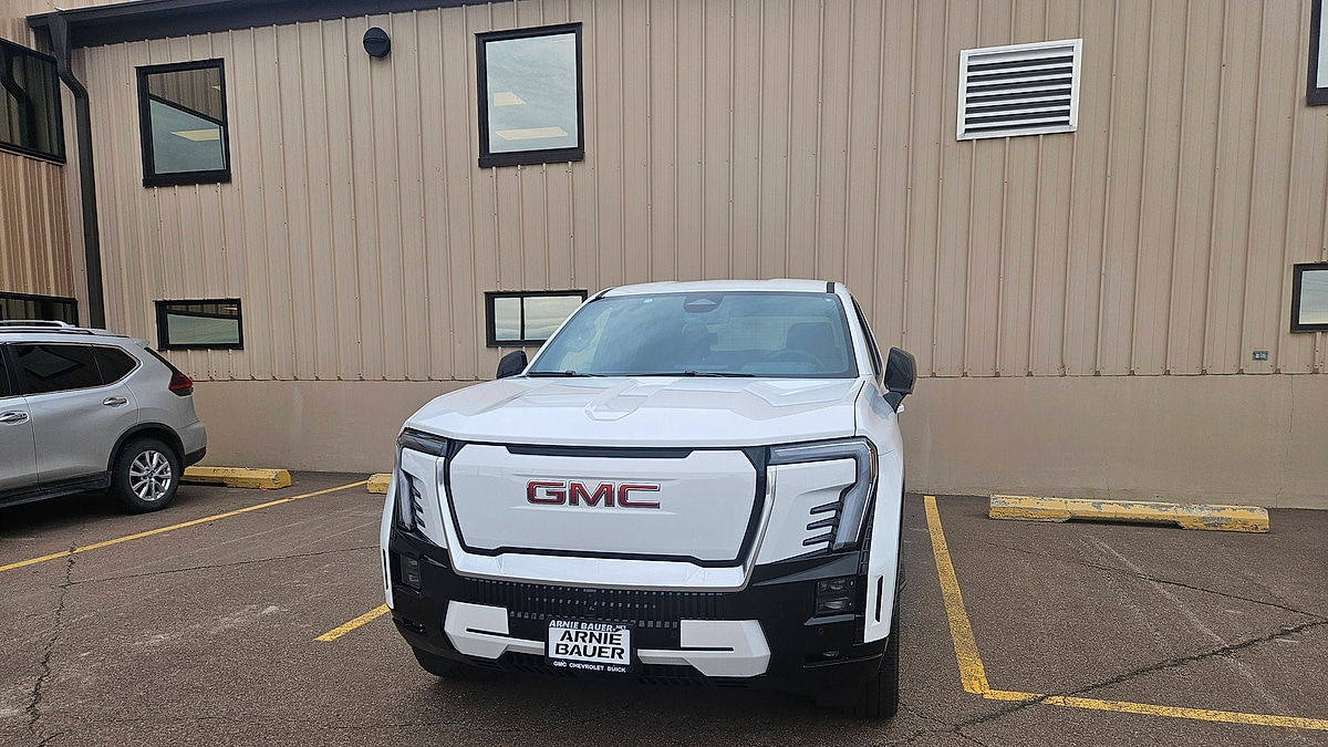 White GMC Sierra EV parked in lot side profile view
