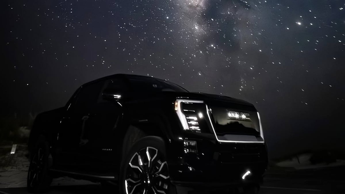 Gregg’s GMC Sierra EV Denali photographed under a star-filled night sky with its signature LED lighting illuminated.