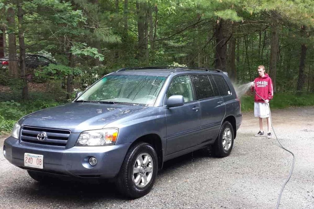 A young man washes a Toyota Highlander