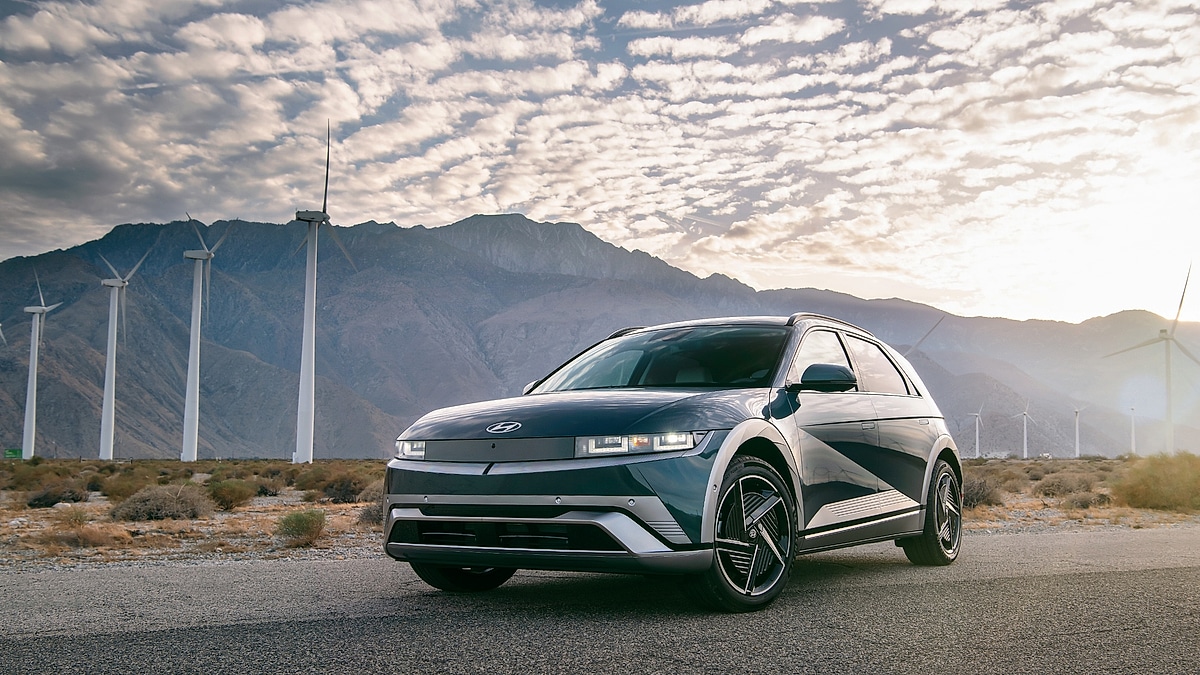 Hyundai Ioniq 5 parked near wind turbines in renewable energy landscape