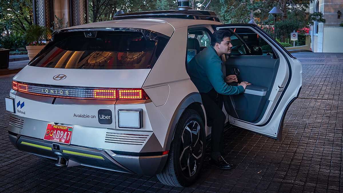 Passenger entering Hyundai Ioniq 5 robotaxi showing rear door access and interior