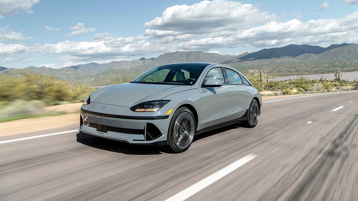 Gray Hyundai Ioniq 6 Limited driving on a desert highway with mountains and a blue sky in the background.