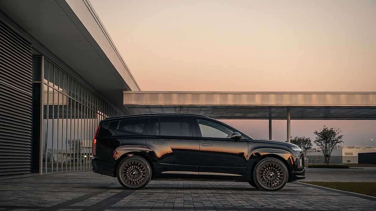 Side profile of a black Hyundai Ioniq 9 parked outside a modern building at dusk.