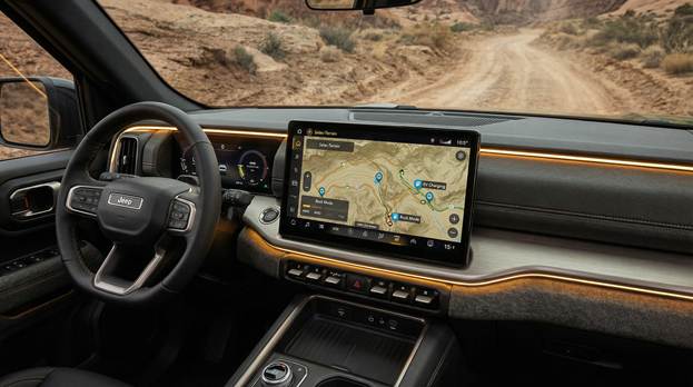 A detailed close-up interior shot showcases the Jeep Recon’s modern dashboard, emphasizing the sleek, 14.5-inch center touchscreen. The screen prominently displays the engaging "Selec-Terrain" off-road pages, complete with a trail map indicating key charging waypoints. Warm interior lighting highlights the high-tech features, creating a sleek and functional ambiance. Through the expansive windshield, a rugged, dusty trail snakes into the distance, hinting at adventures waiting beyond. The rich textures and materials of the dashboard add depth to the image, presenting a blend of technology and nature ready for exploration.