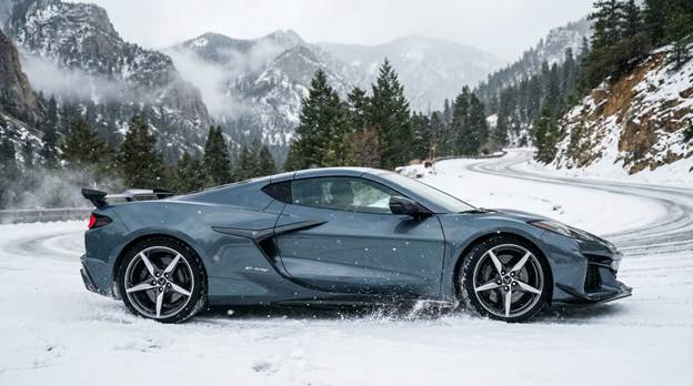 A striking side profile shot of a Sea Wolf Gray Corvette E-Ray expertly navigating a snowy mountain pass, its sleek design showcasing the car's dynamic lines and aggressive stance. The rugged landscape contrasts with the polished exterior, emphasizing its all-weather AWD capability. Soft snowflakes drift gently around, adding a sense of movement and drama. The ambient light reflects off the snow and the car's surface, enhancing the glossy finish. In the distance, misty peaks and evergreen trees frame the scene, creating a breathtaking backdrop that captures the thrill and adventure of driving in challenging conditions.