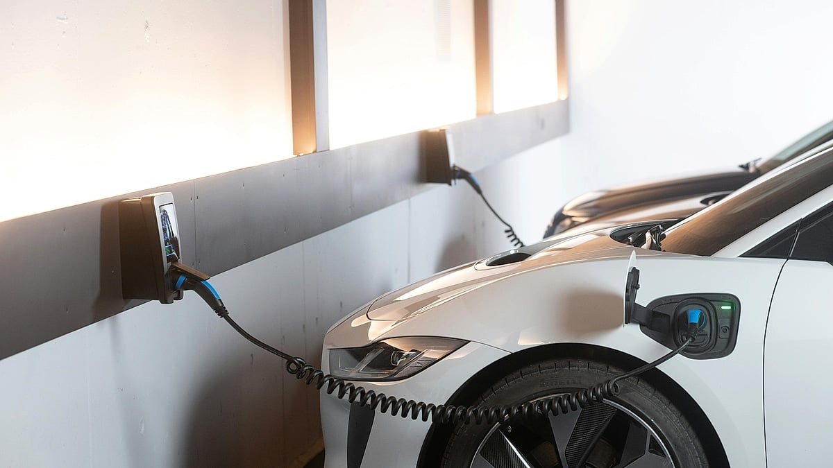 White Jaguar I-Pace charging at an indoor wall-mounted EV charger.