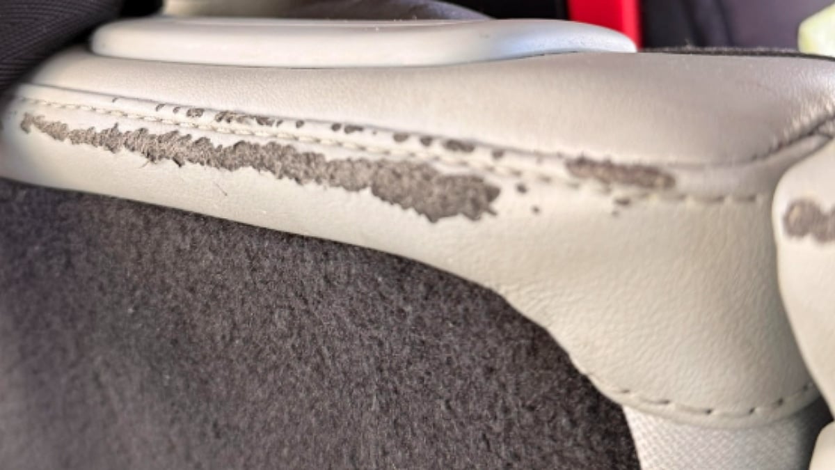 Rear seatbacks inside Kate's 2023 Rivian R1S showing significant deterioration and peeling along the upper edges of the light-colored seat material.