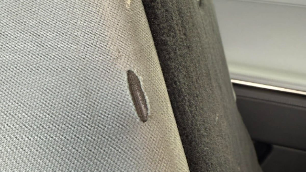 Close-up image of interior fabric trim inside Kate's 2023 Rivian R1S showing a vertical tear in the light-colored material that exposes darker material beneath the surface.