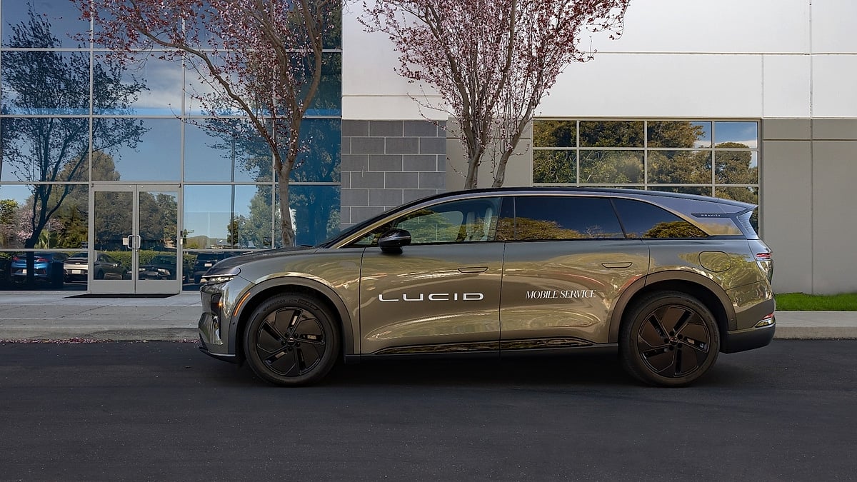 Lucid Gravity electric SUV side profile with mobile service branding parked near office building