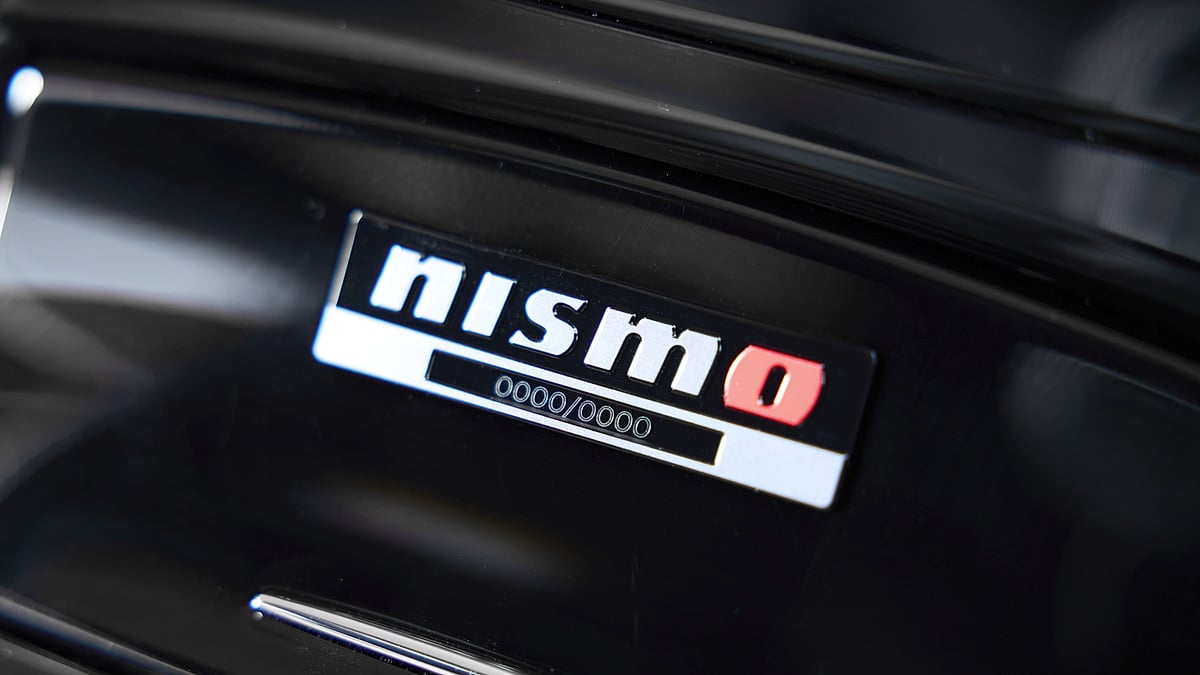 Close-up of Nismo limited edition numbered sequential badge on black body panel showing production number placeholder