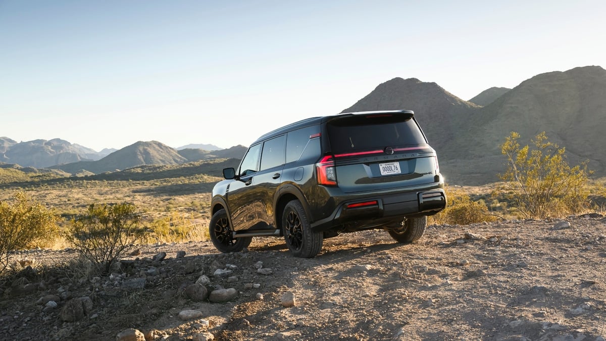 Black Nissan Armada SUV parked on a rocky desert trail, rear three-quarter view with mountains in the distance