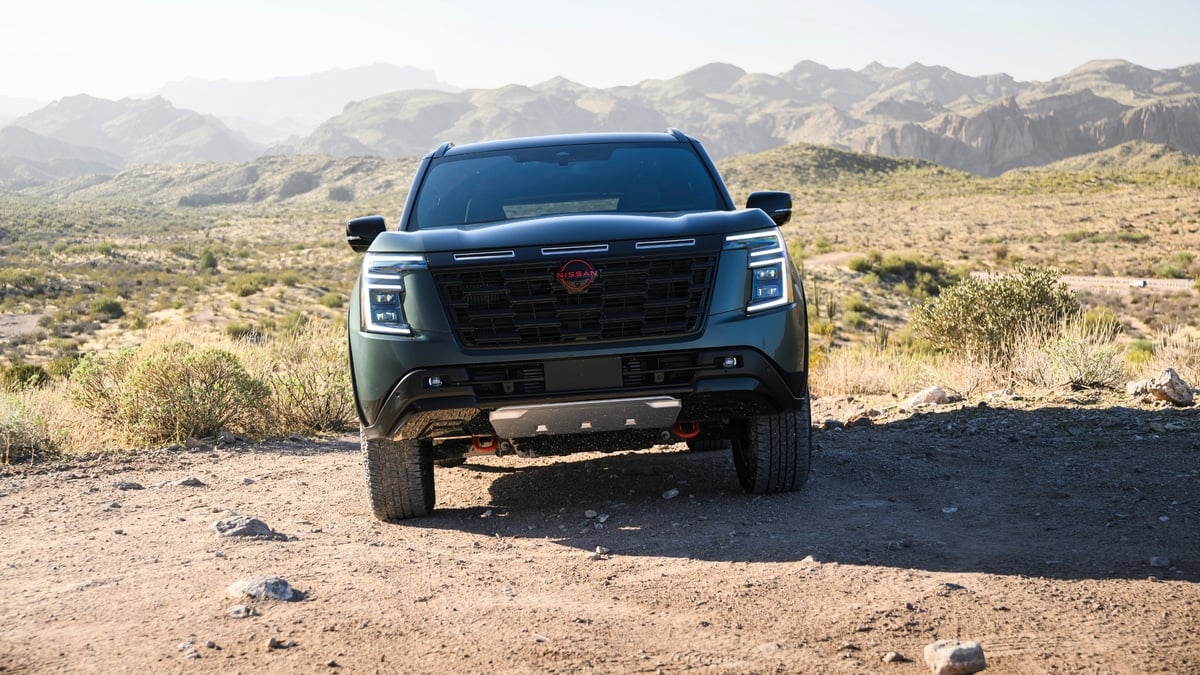 Dark green Nissan Armada SUV parked on a desert trail, straight-on front view with mountains in the background
