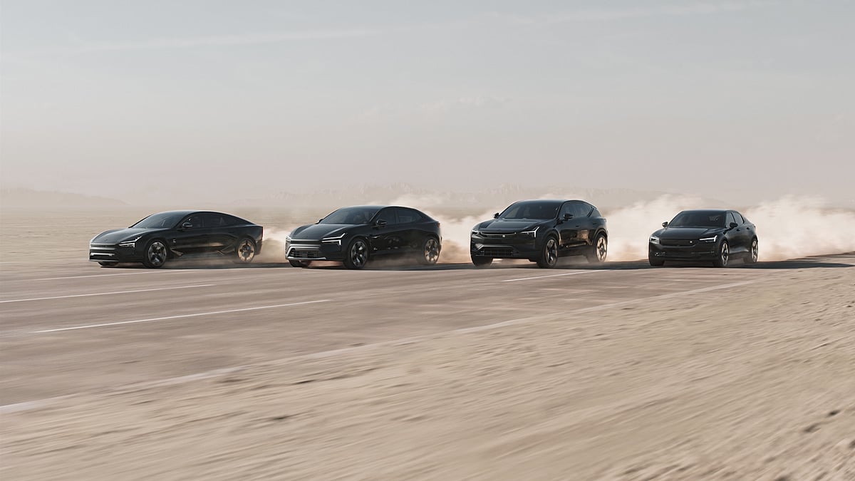 Four black Polestar electric vehicles driving across a dusty desert road in a wide formation.