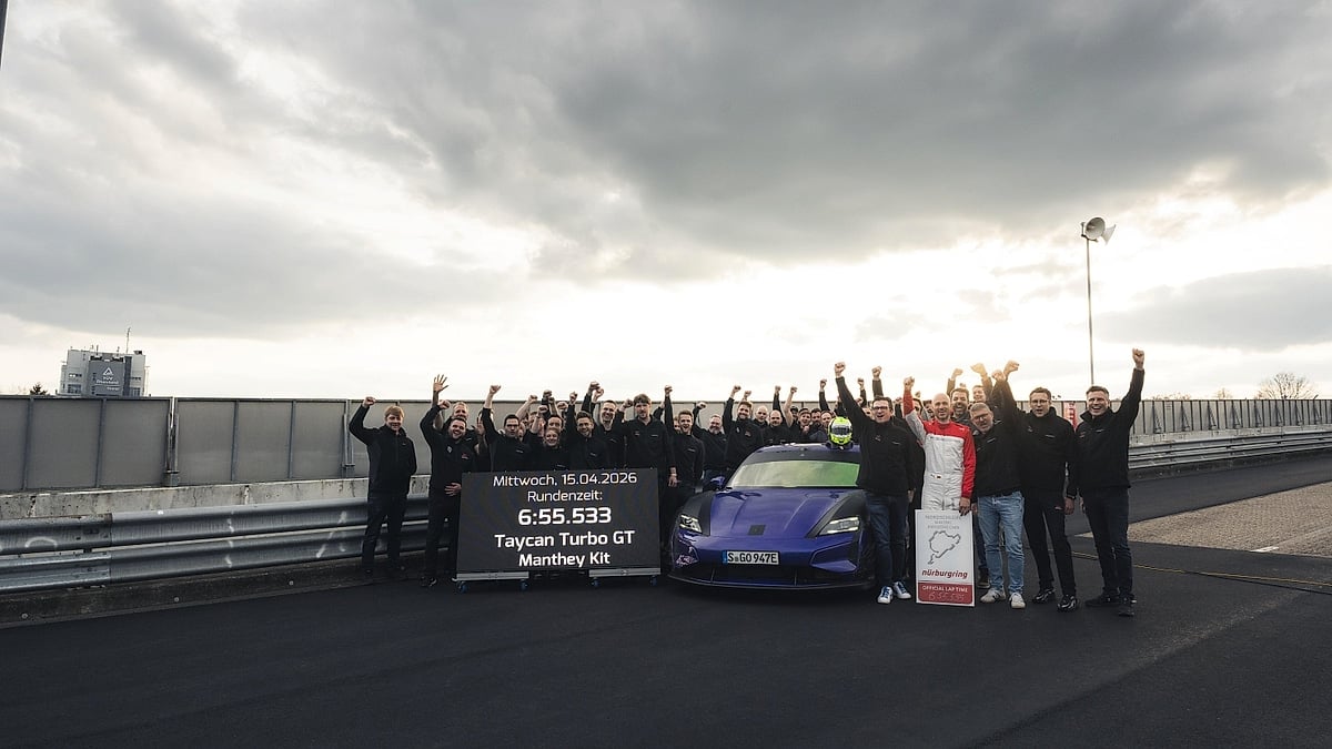 Porsche Taycan Turbo GT with Manthey Kit surrounded by a team celebrating a Nürburgring lap record.