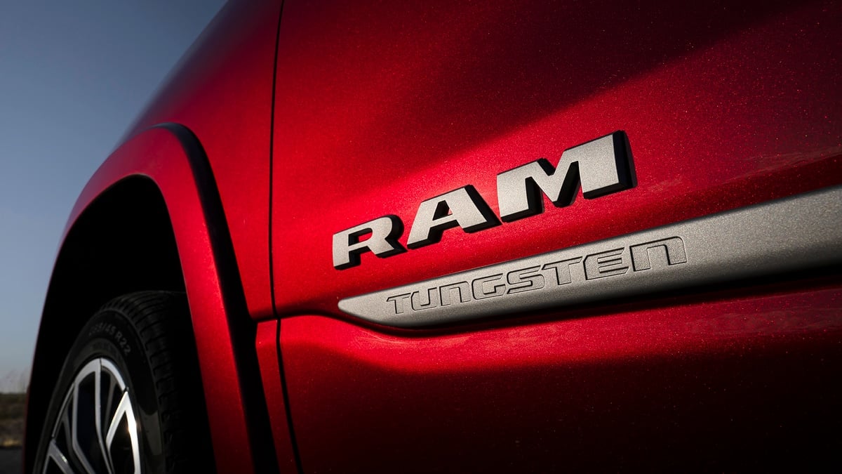 Close-up of the Ram Tungsten badge on the fender of a red Ram 1500 pickup truck