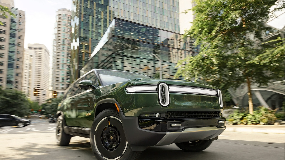 Rivian R1S electric SUV driving through city street with modern buildings