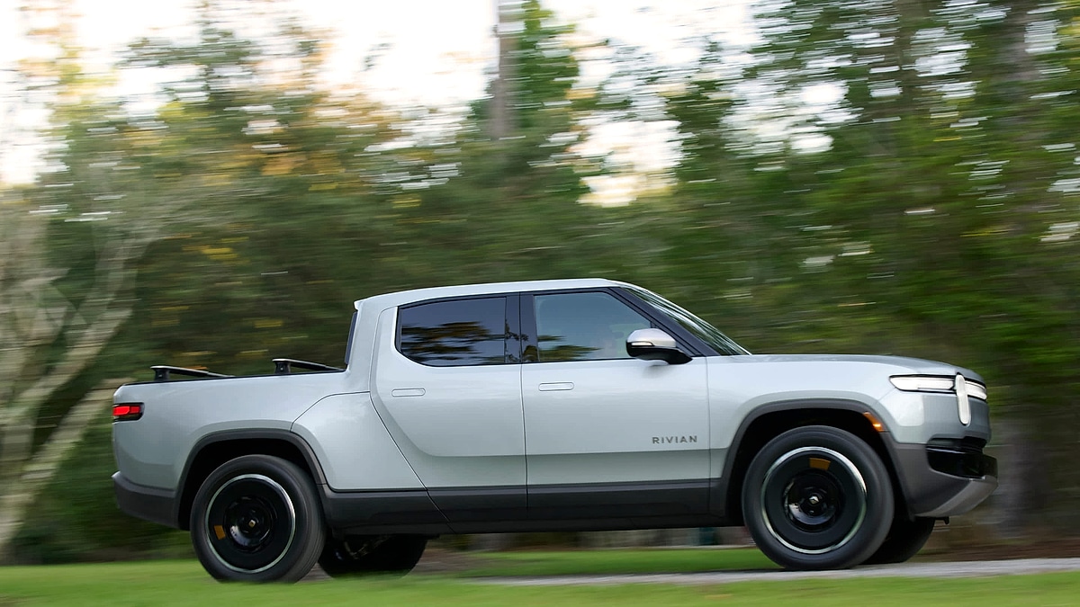 Rivian R1T electric pickup driving on road with motion blur
