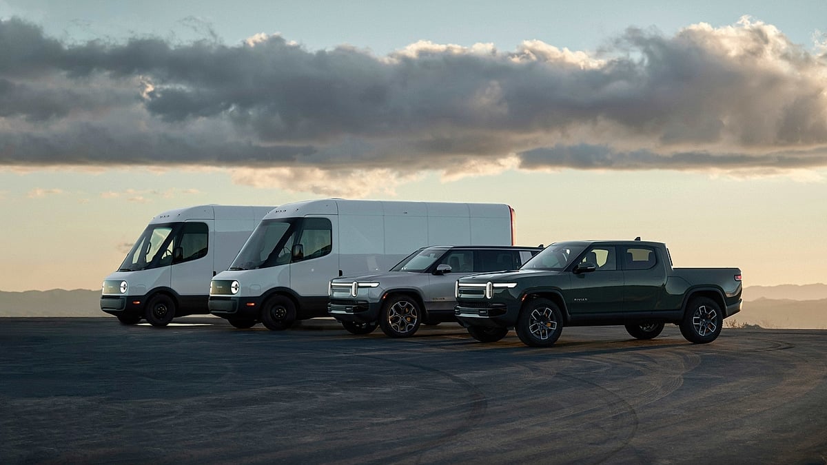 Rivian electric fleet lineup with delivery vans, an R1S SUV, and an R1T pickup parked at sunset.