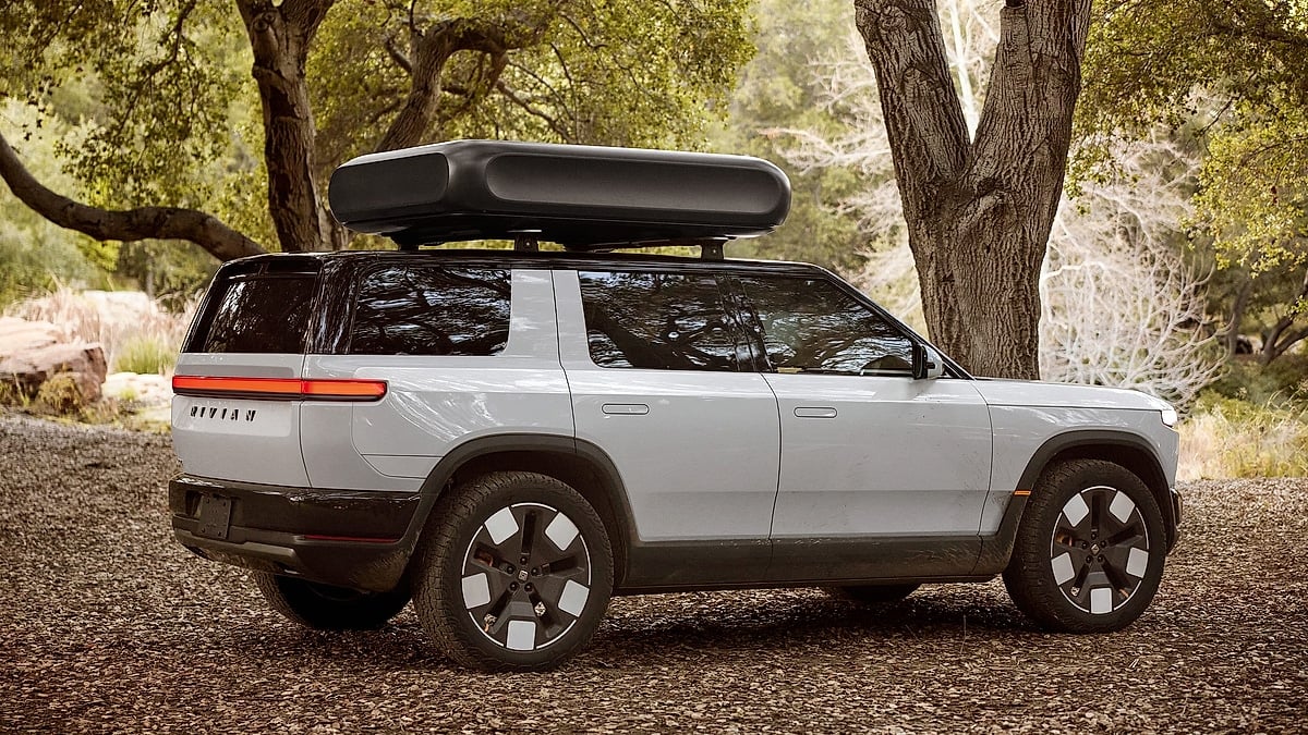Rivian R2S electric SUV side profile with roof cargo box parked under trees