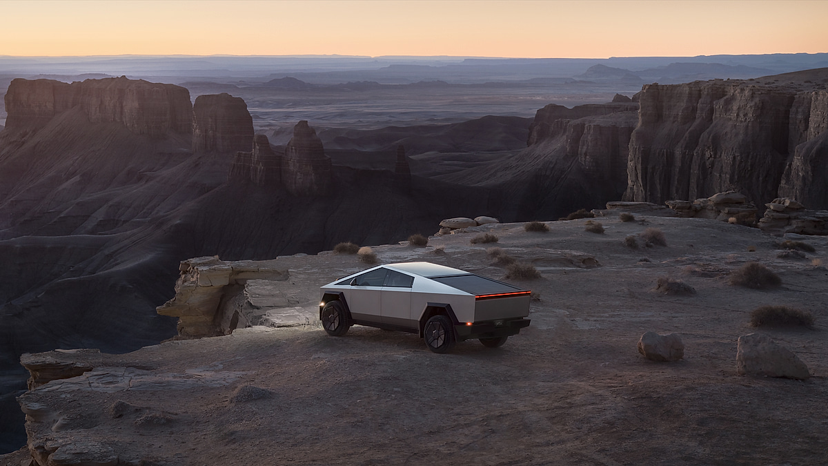 Tesla Cybertruck parked on canyon cliff at sunset with dramatic landscape