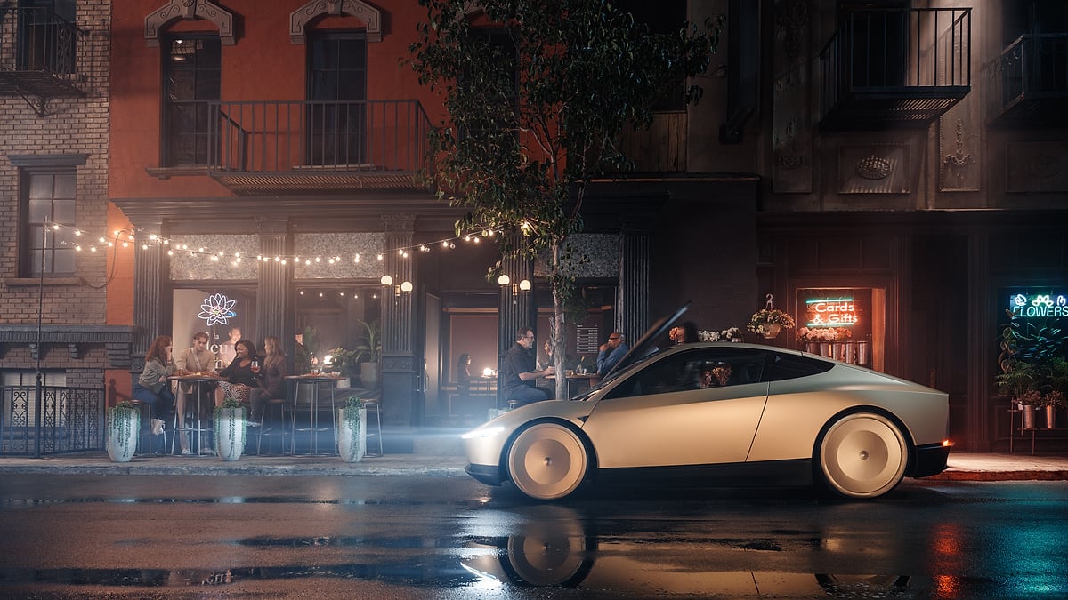 Tesla Cybercab parked on a wet city street at night outside a cafe and flower shop.