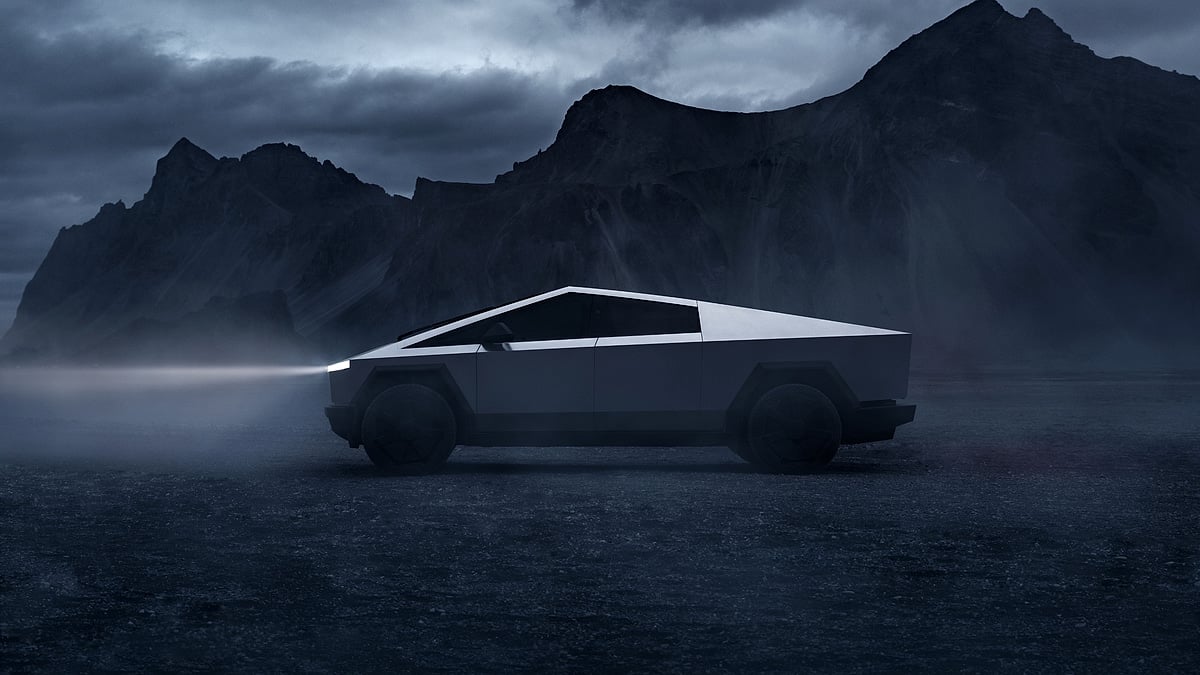 Tesla Cybertruck shown in side profile on a dark mountain road with dramatic storm clouds overhead.